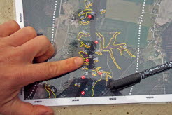 Finger som pekar på karta med markeringar i olika färger.