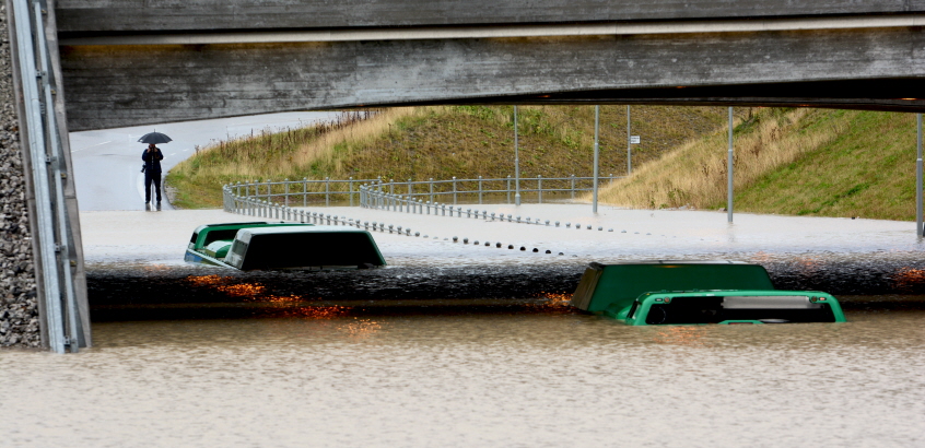 Buss sitter fast i vattenmassorna under en viadukt. 