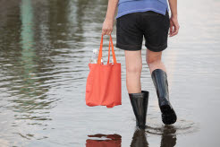 Underkropp på tjej som går på en översvämmad gata med stövlar.