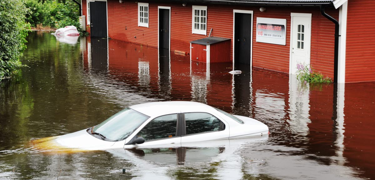 Bil och ladugård som har blivit översvämmade.