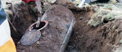 Saneringsarbete vid en mack. En tank lyfts upp ur jorden av en grävskopa.