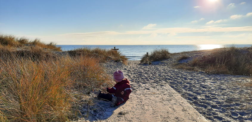 Bild från en strand med en liten flicka på.