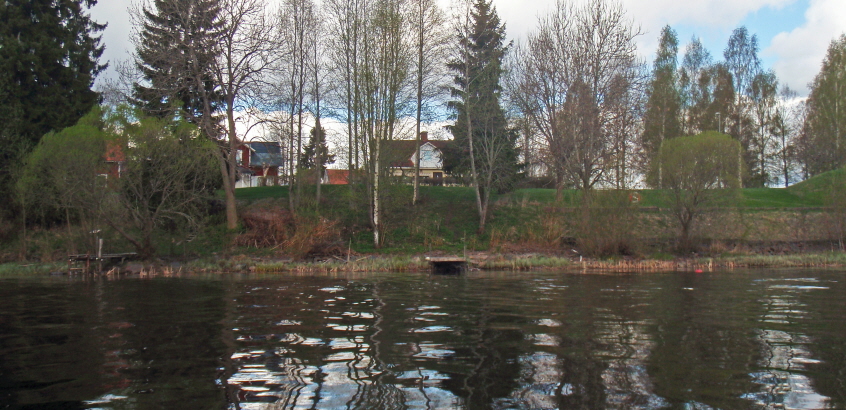 Hus vid Norsälven. Fotot är taget ut ifrån vattnet in mot land.