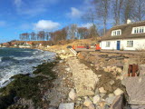 Erosionsskada vid strand. Hus byggt intill.