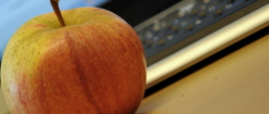 Ett äpple som ligger framför ett tangentbord.