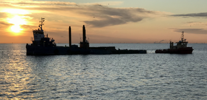 Siluett av en stor flotte på vatten i oran-gefärgat motljus