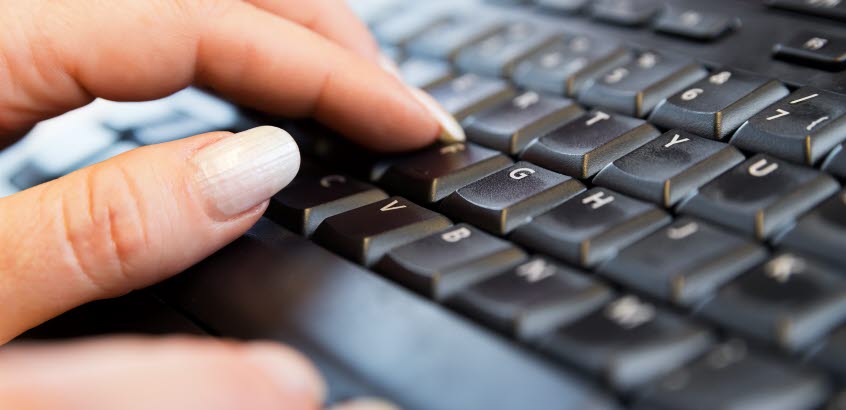 Närbild på en kvinnohand som skriver på ett tangentbord.